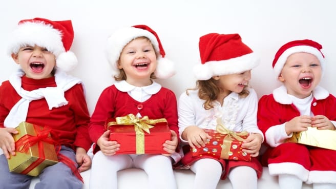 Four cute kids dressed for the holiday, and celebrate Christmas.