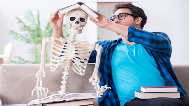 A funny person play with the skeleton will learning on the human body.