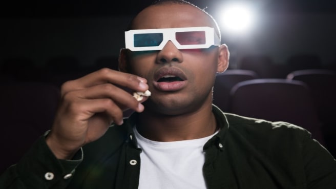 A young man watching a movie in the cinema.