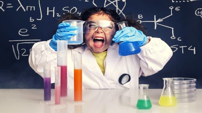 A funny little scientist practice science and smiling.