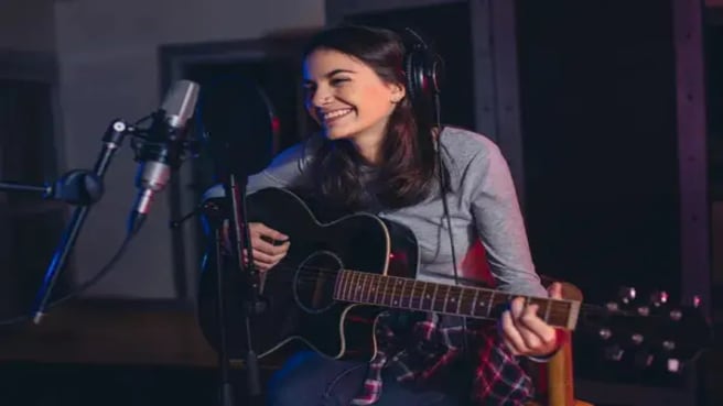 A Female singer playing guitar and singing a song.