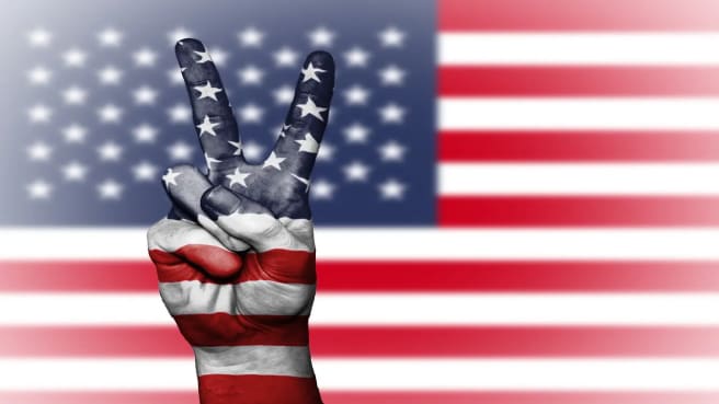US flag with a hand making the peace sign.