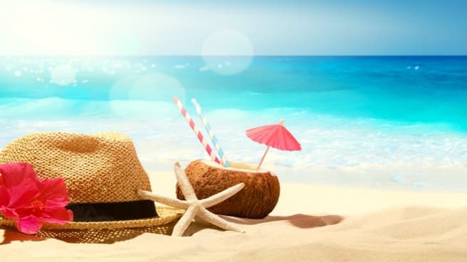 A hat and coconut on the beach during summer.