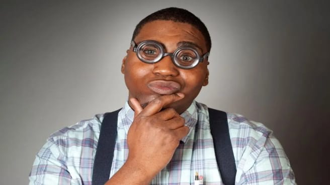 A funny man with big glasses is thinking hard on the world's hardest quiz.