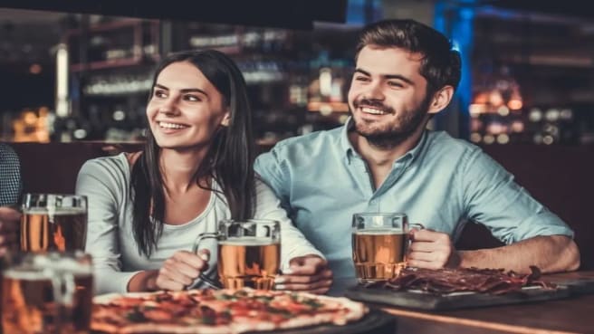A couple is sitting in a bar participating in bar trivia.