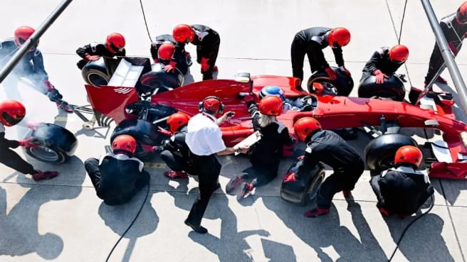 An F1 car is getting its tires replaced.