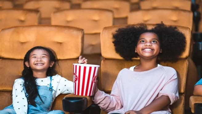 Two young girls watching a kid's movie in the cinema.