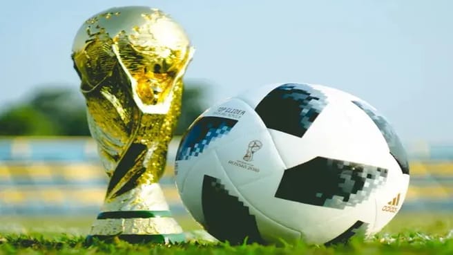 World Cup trophy and a soccer ball on a soccer court grass.