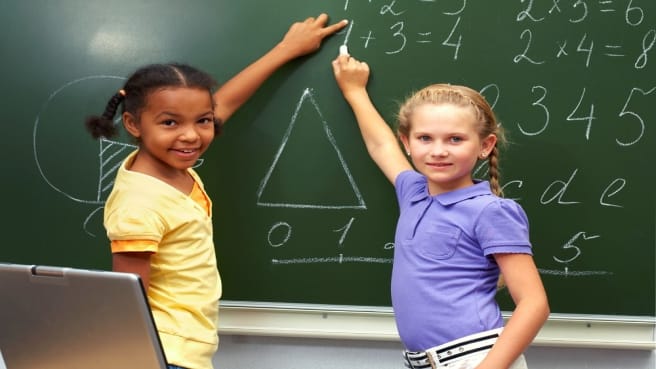 Two 4th grade girls with a math chalkboard.