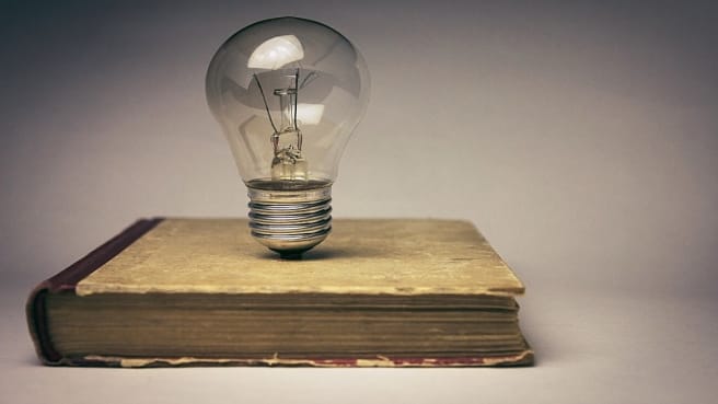 An old general knowledge book with a light bulb above it.