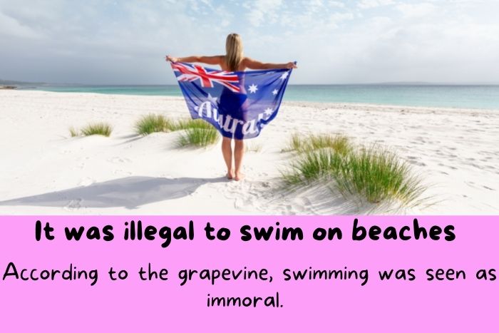A woman with Australia's flag on the beach, near the sea. 