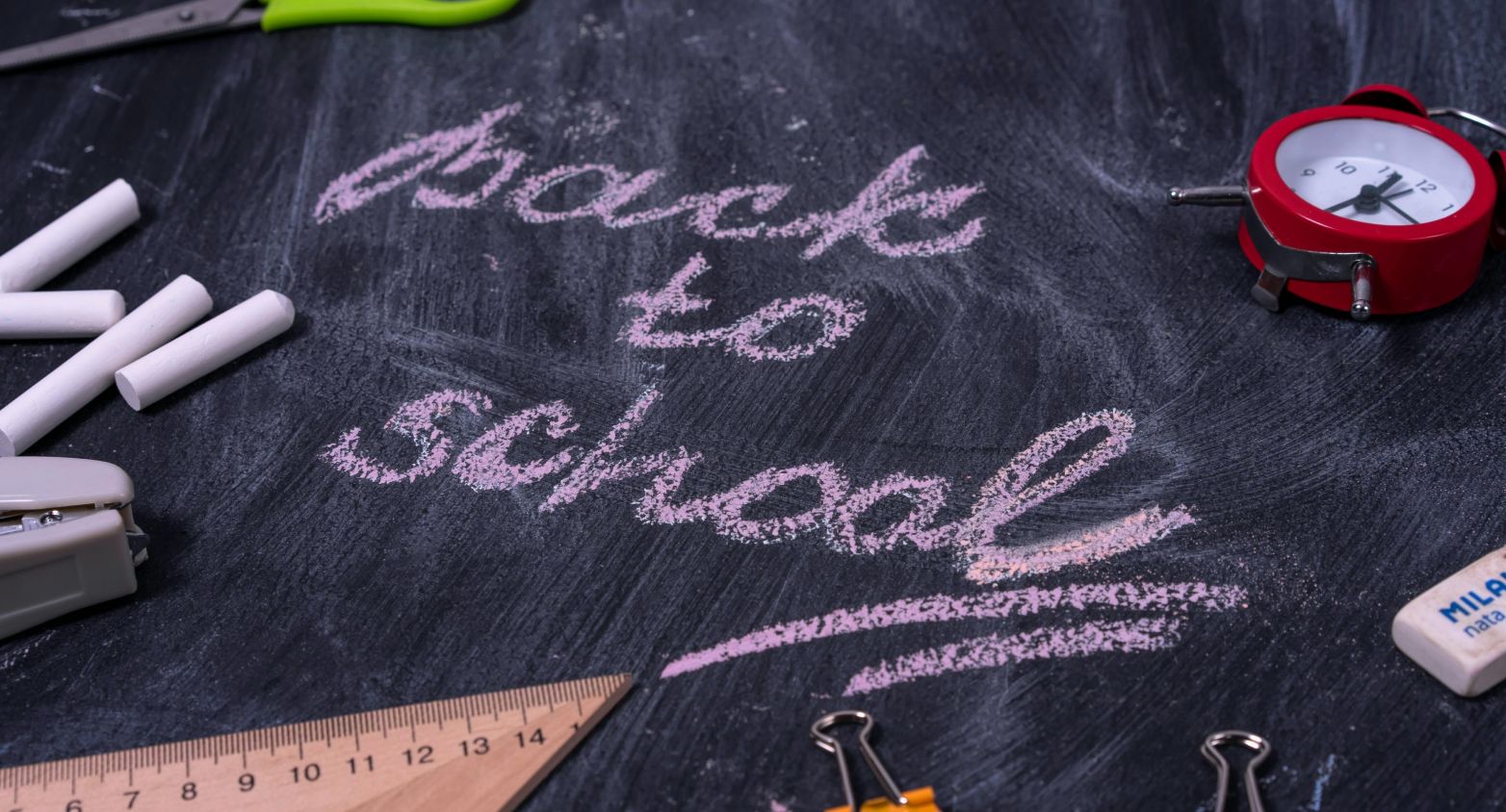 Board with 4 withe chalks, a clock, and the sentence: "Back to school"