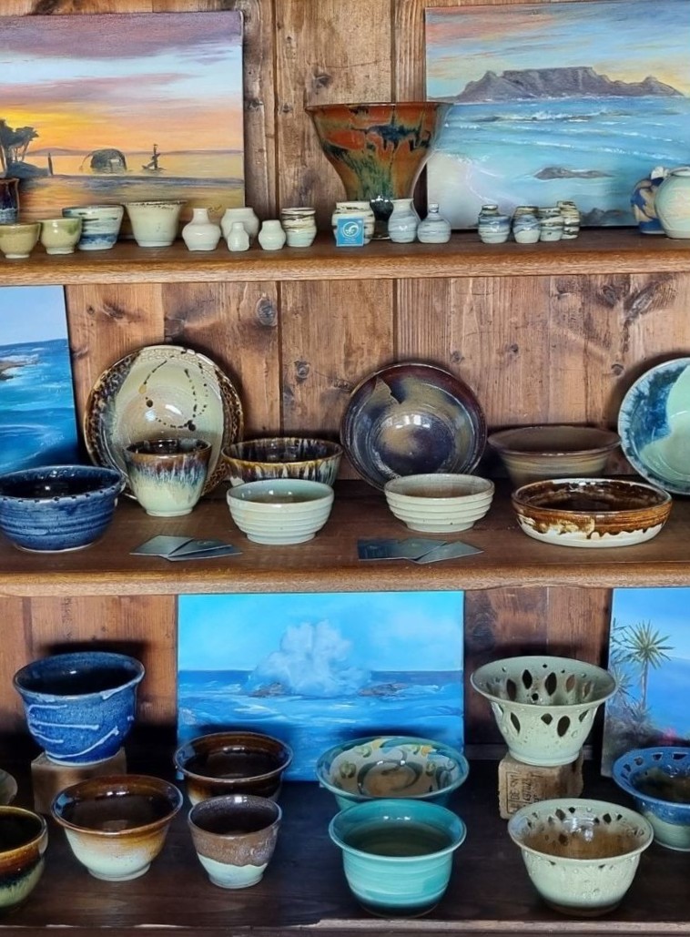 Pottery and artwork displayed on wooden shelves