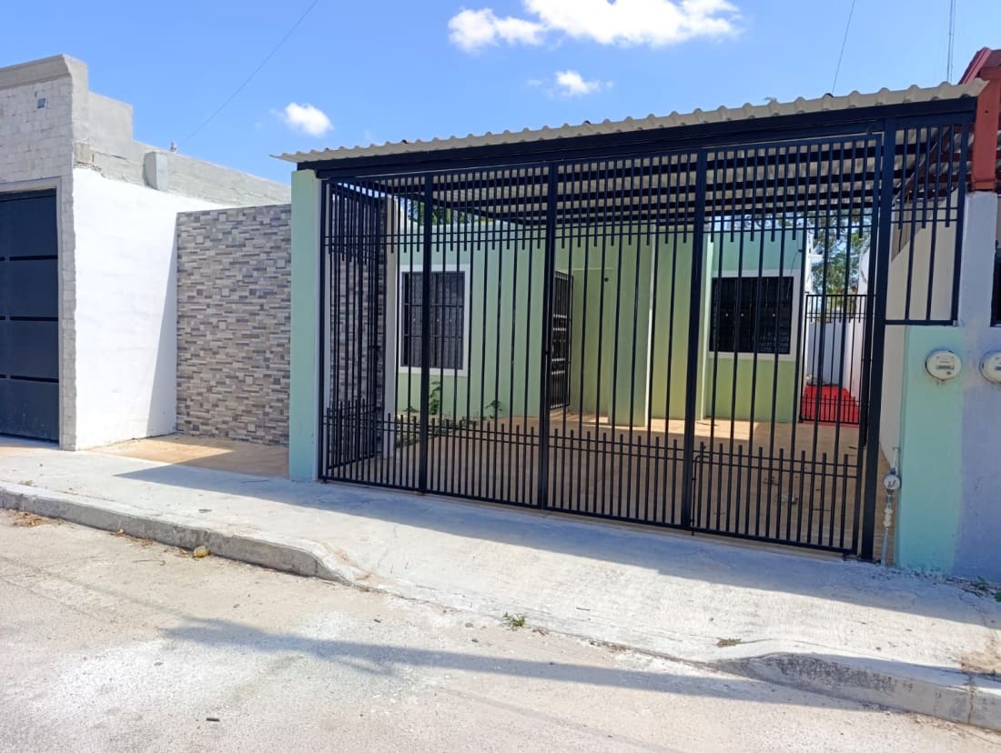 Casa o local con puerta metalica negra, pared blanca, zocalo gris, techo naranja