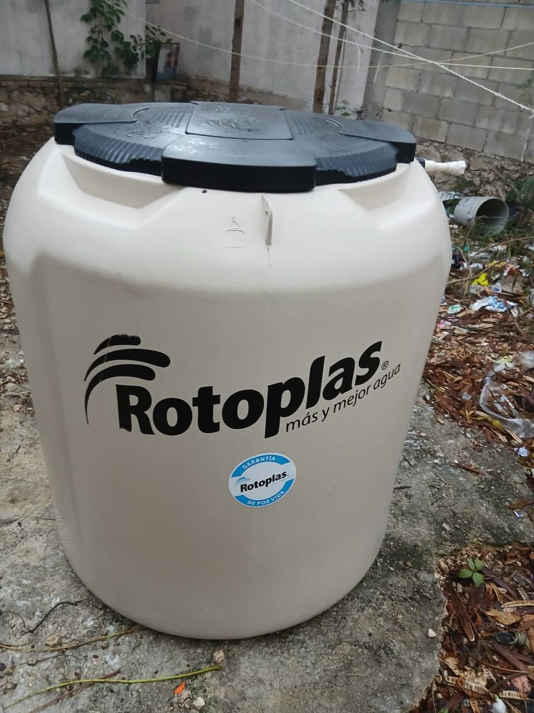 Tanque de agua Rotoplas blanco con tapa negra, logo y texto de marca visible