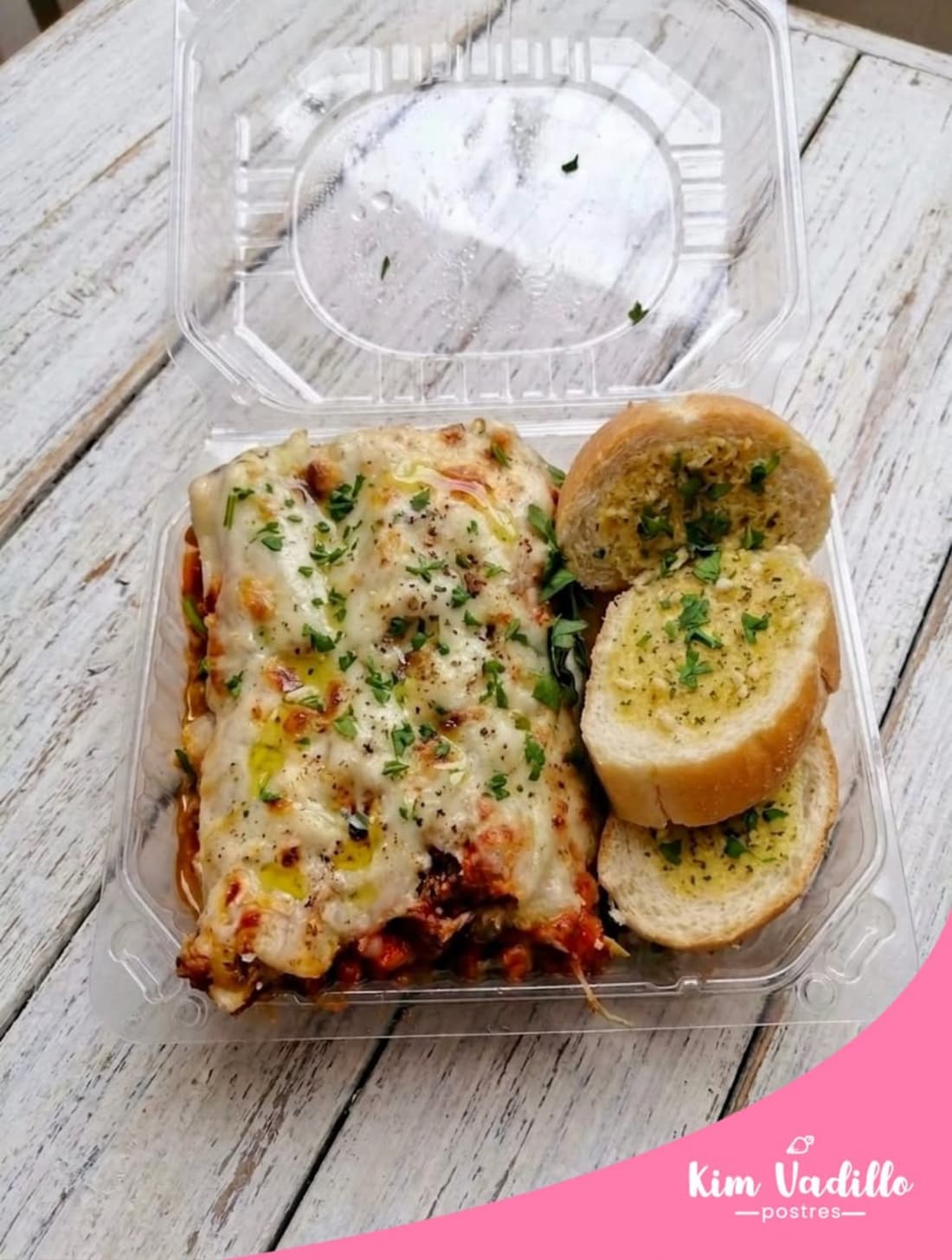 Caja de plastico con relleno blanco, pan tostado con queso derretido y salsa roja, marca kim Vadillo postres.