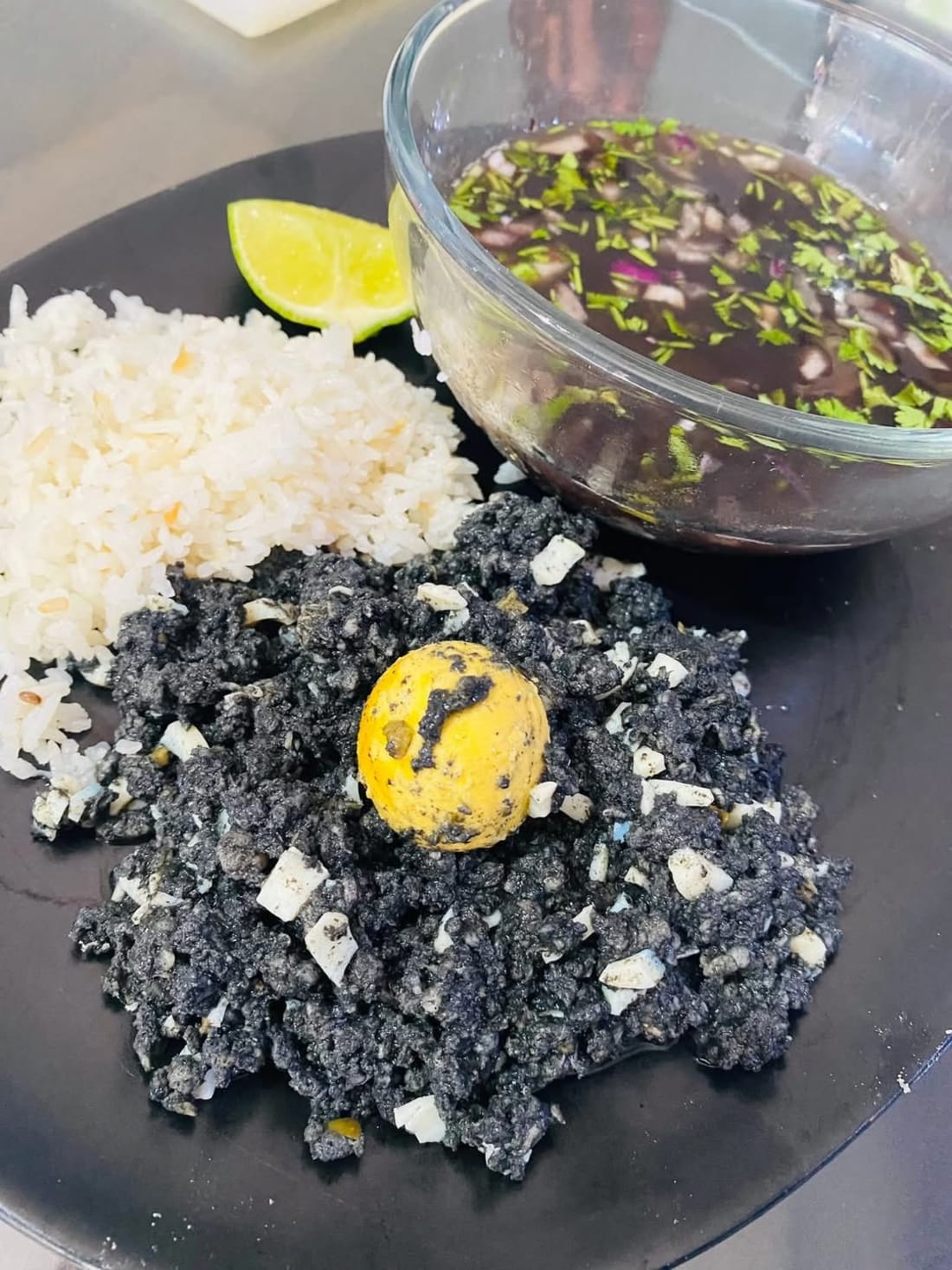 Platillo con camarones negros al ajillo, arroz blanco y salsera con cilantro verde.