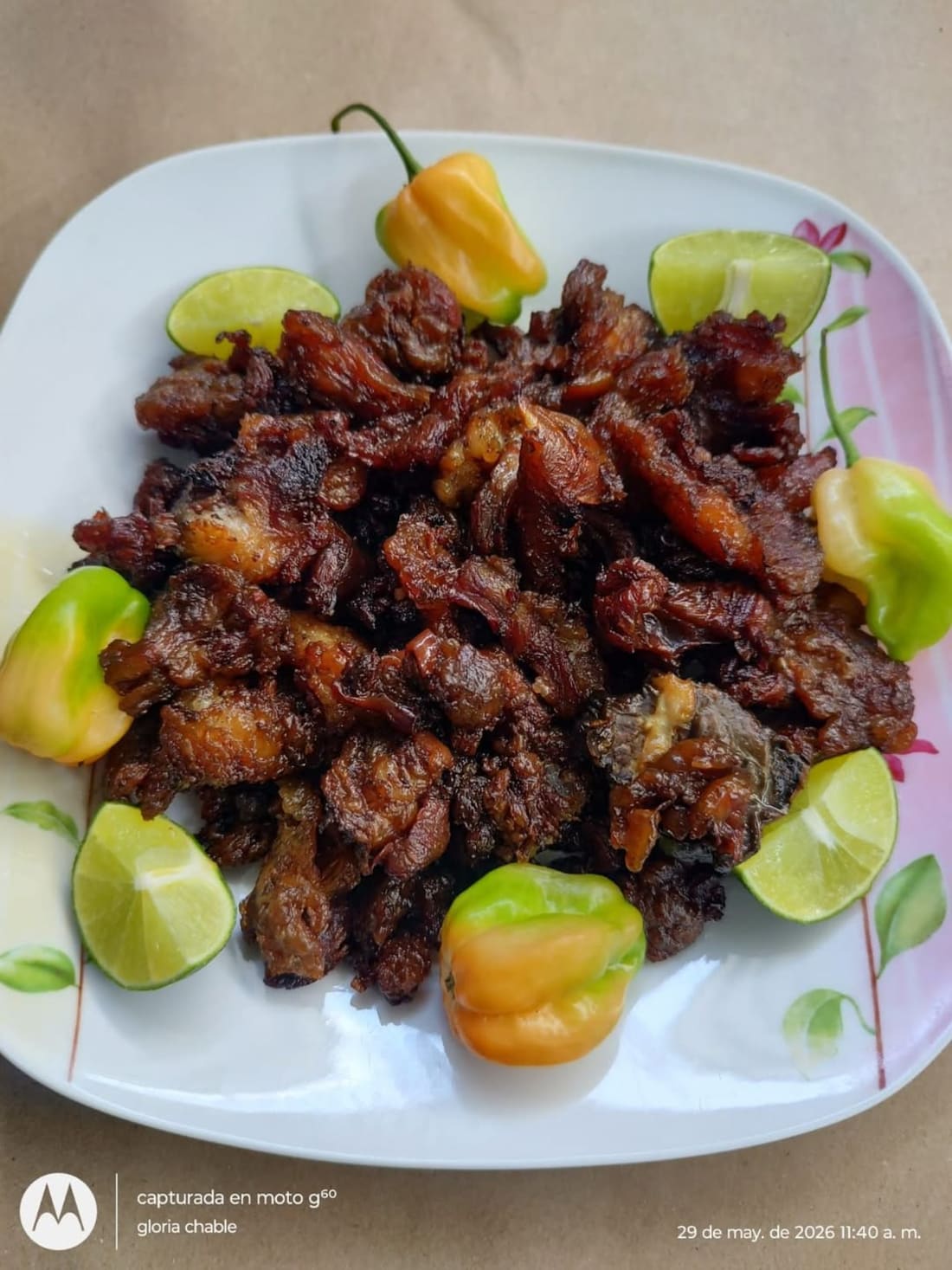 Plato blanco con carne asada especiada, garnish de peppers y limones, firma gloria chable en esquina.