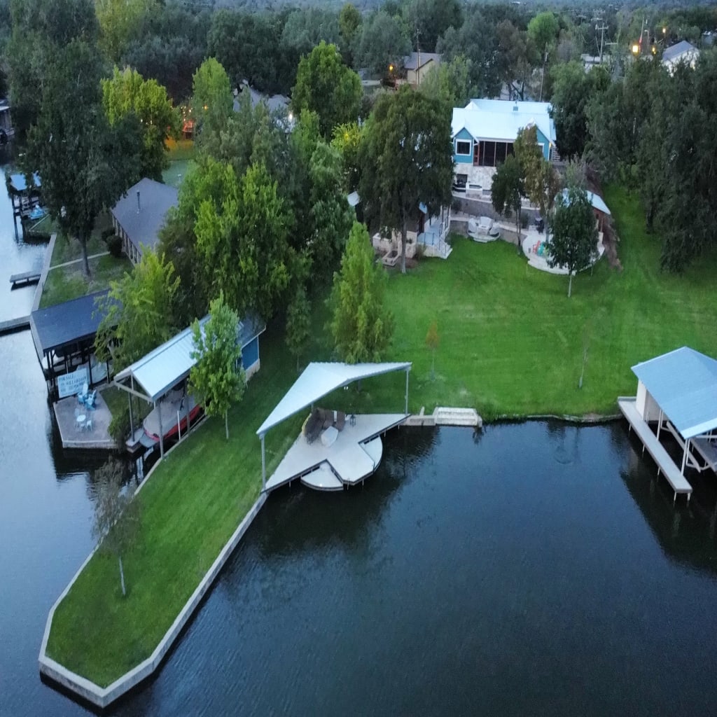 Lakefront estate property with dock, lawn, and multiple outdoor living zones