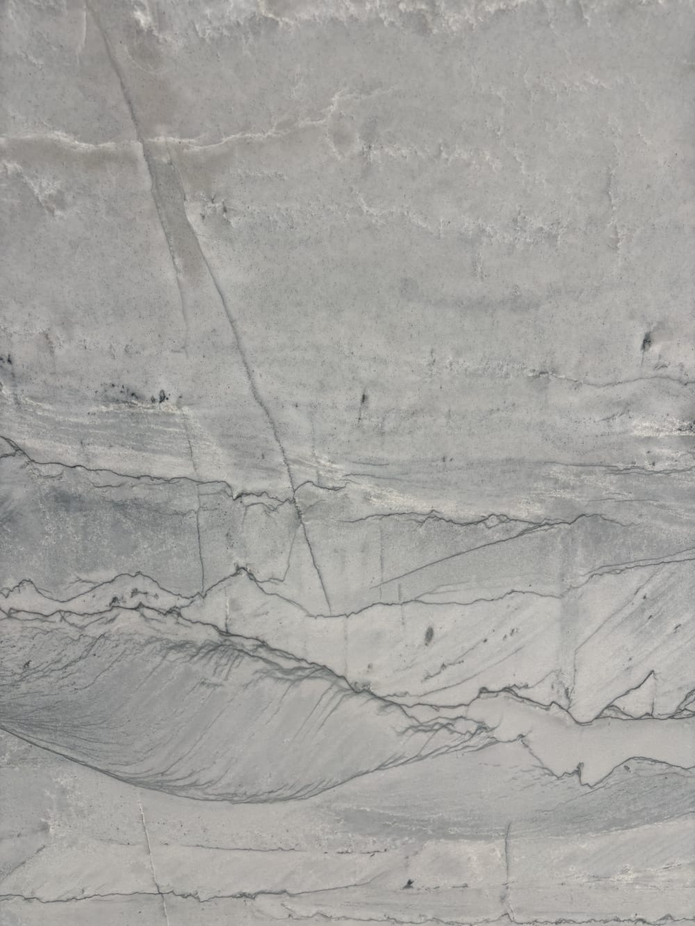 Maldives quartzite detail, darker grey strata stepping and fracturing across a pale grey ground