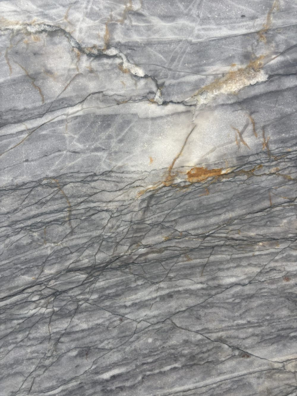 Manhattan quartzite detail, amber and rust veining cutting through fine grey striations