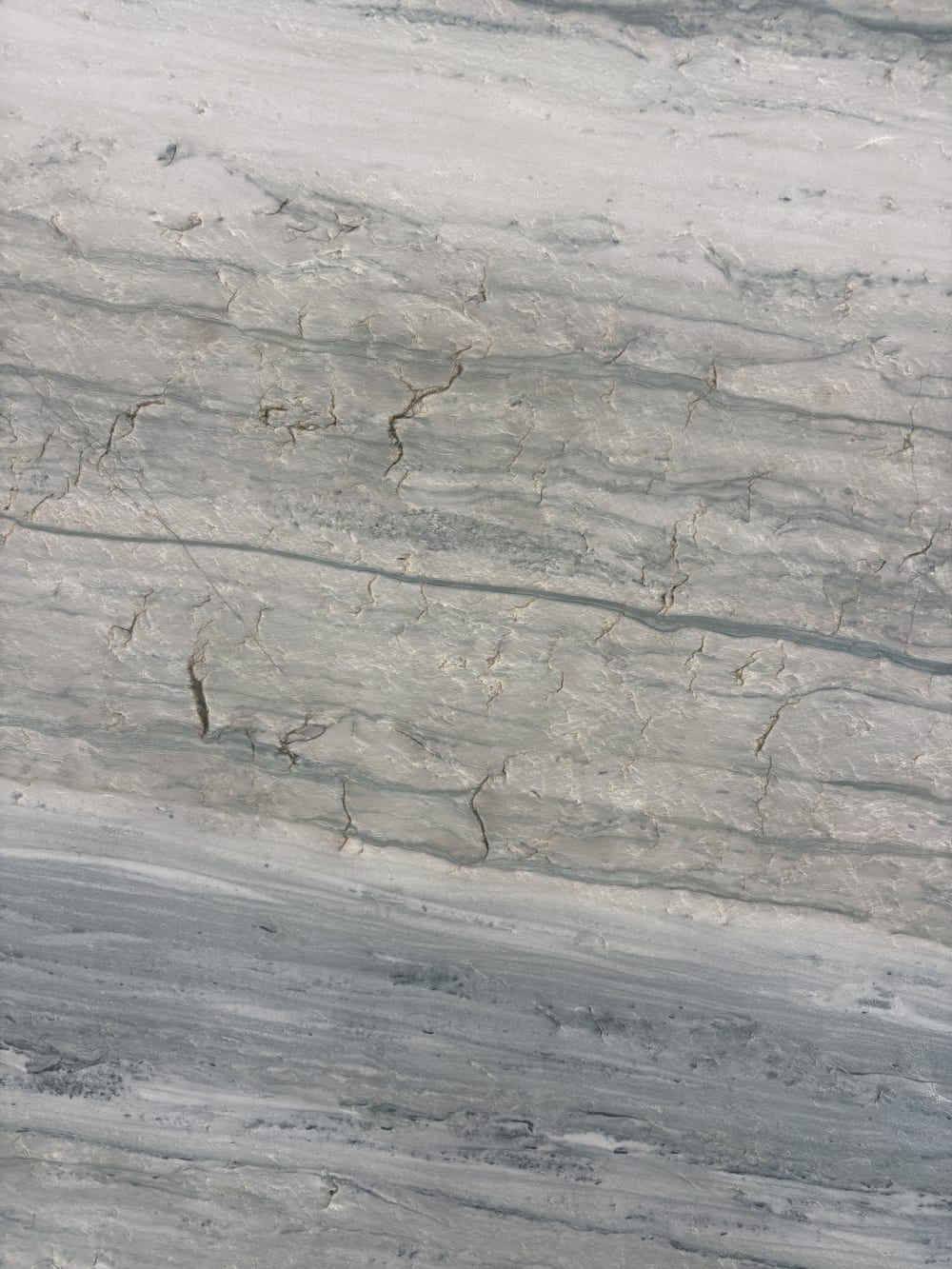Alpine quartzite detail, fine horizontal grain crossed by faint olive-gold seams