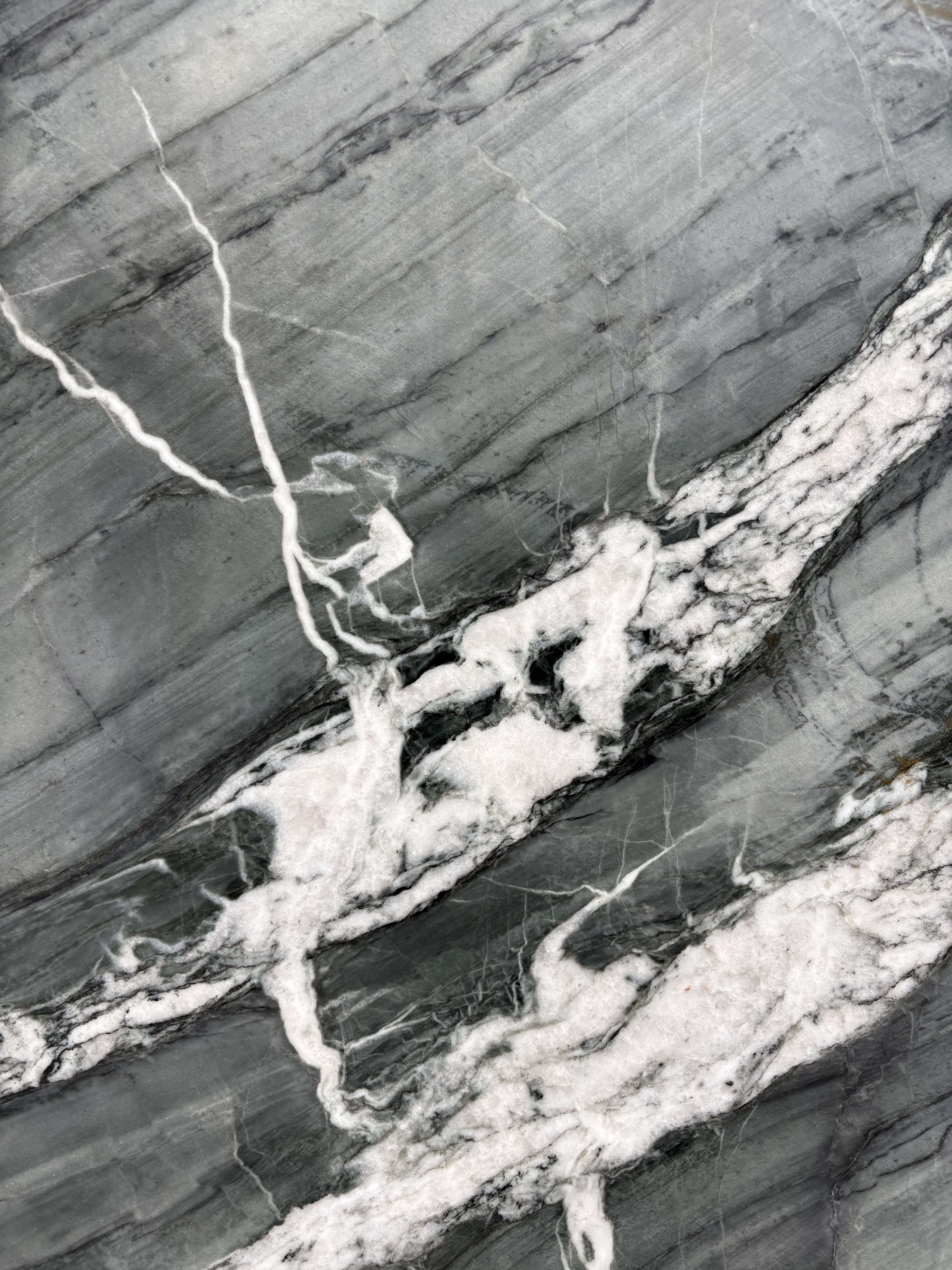 Serra Gris quartzite detail, bright white quartz veining cutting across grey striations