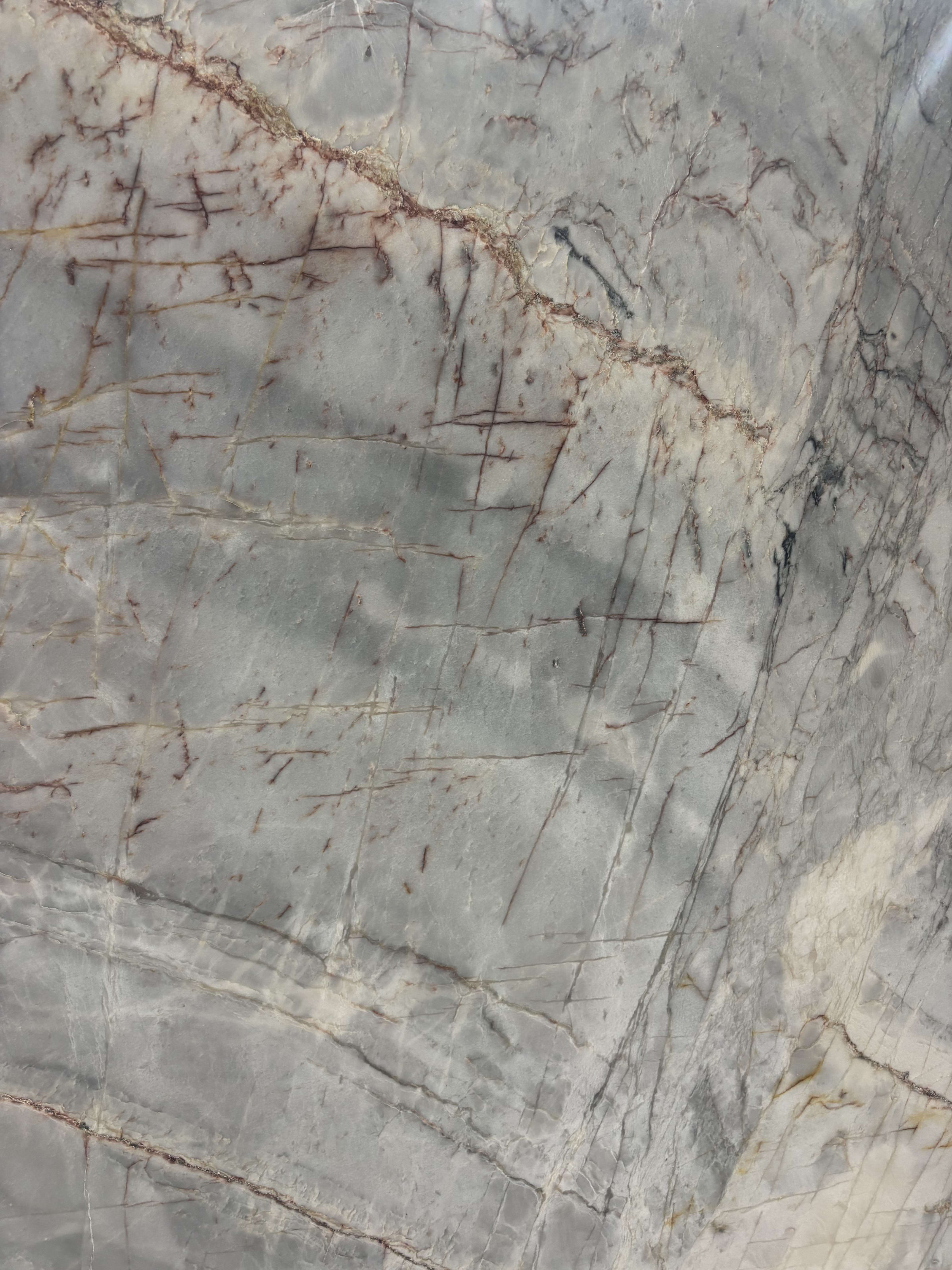 Essenza Aqua quartzite detail, fine hairline red veining scattered across a blue-grey ground