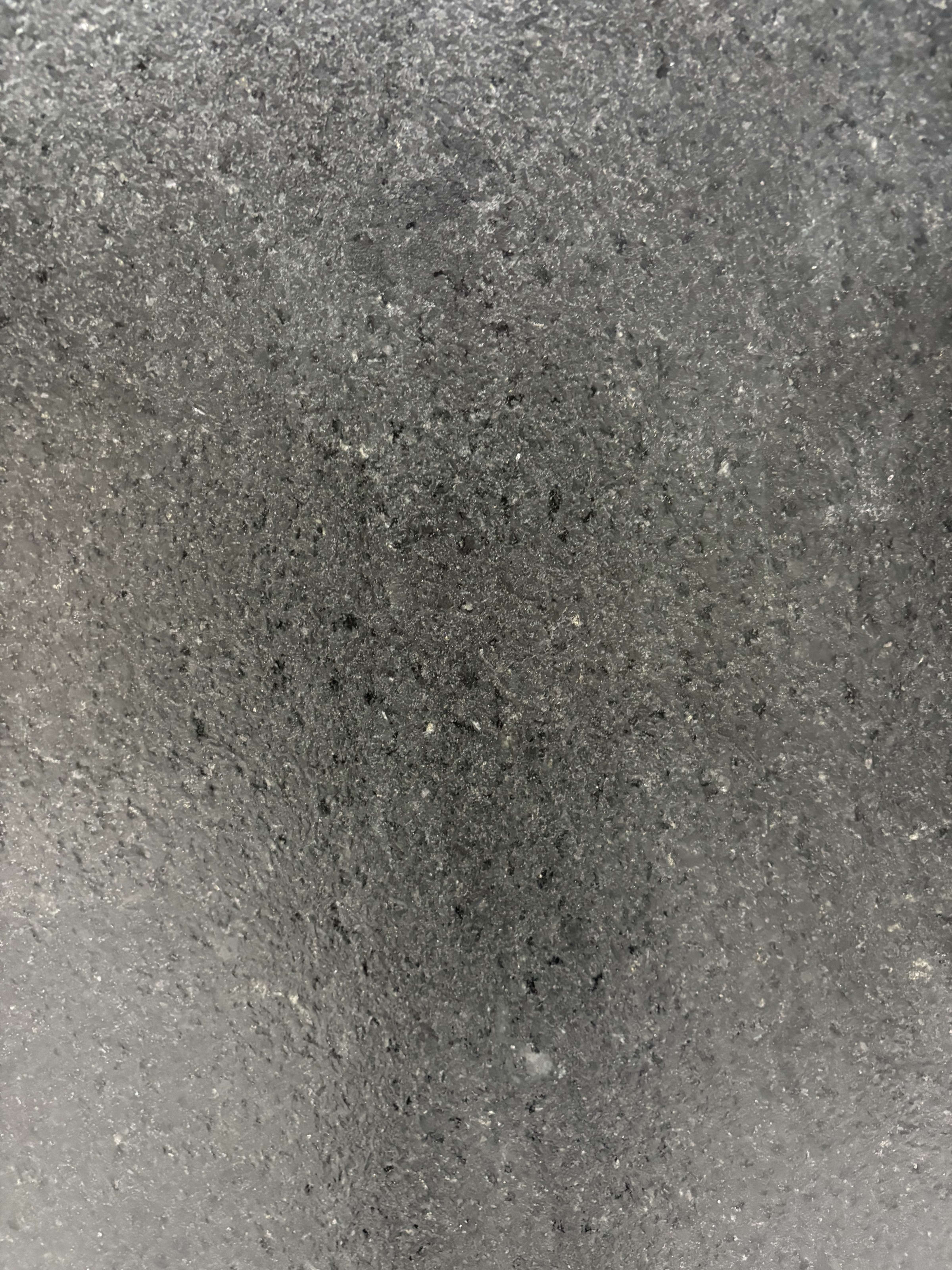 Brazilian Black granite detail, leathered texture with faint mineral fleck across a dense black ground