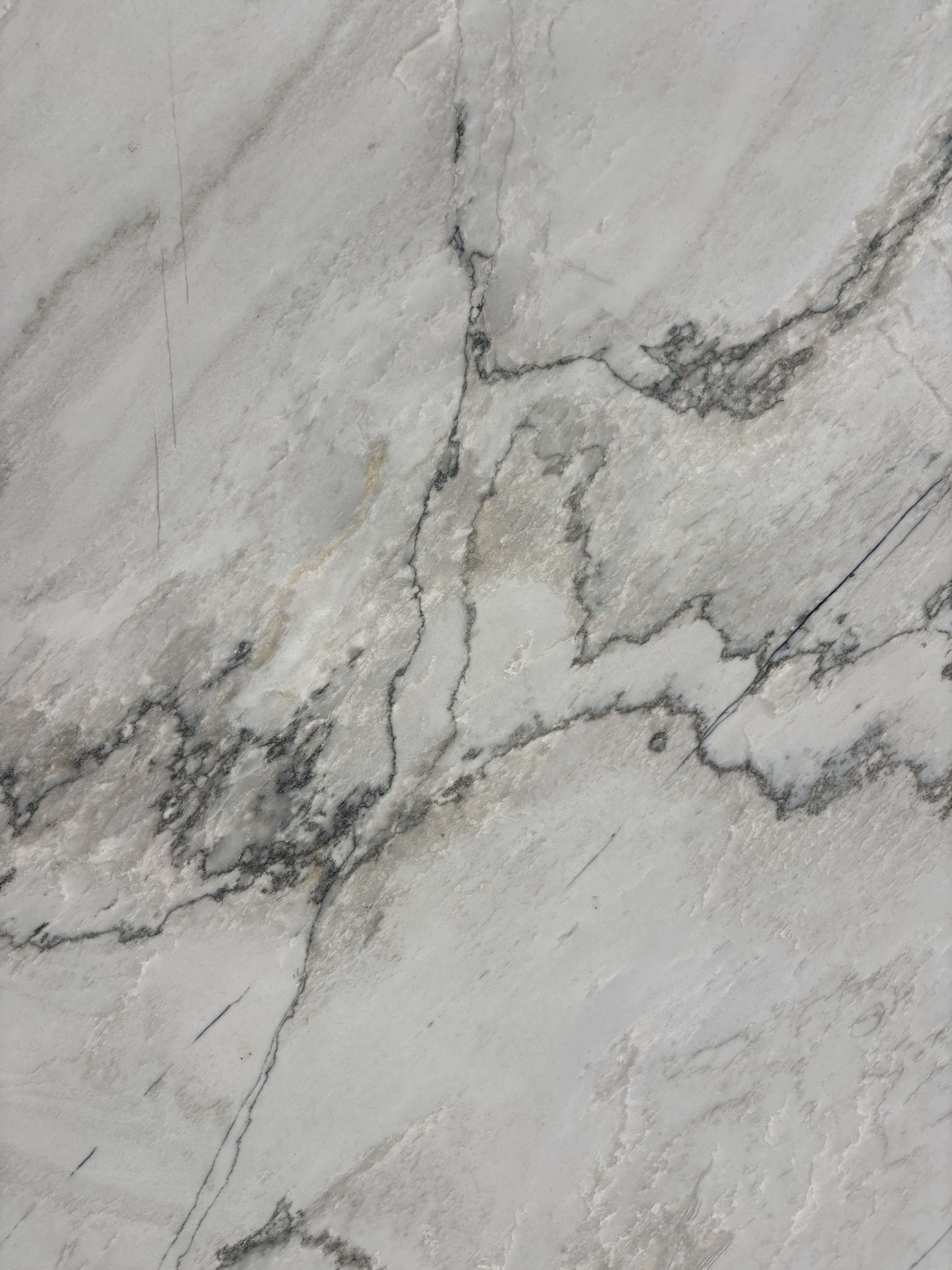 White Santorini quartzite detail, fine grey veining meandering across a soft white-grey ground