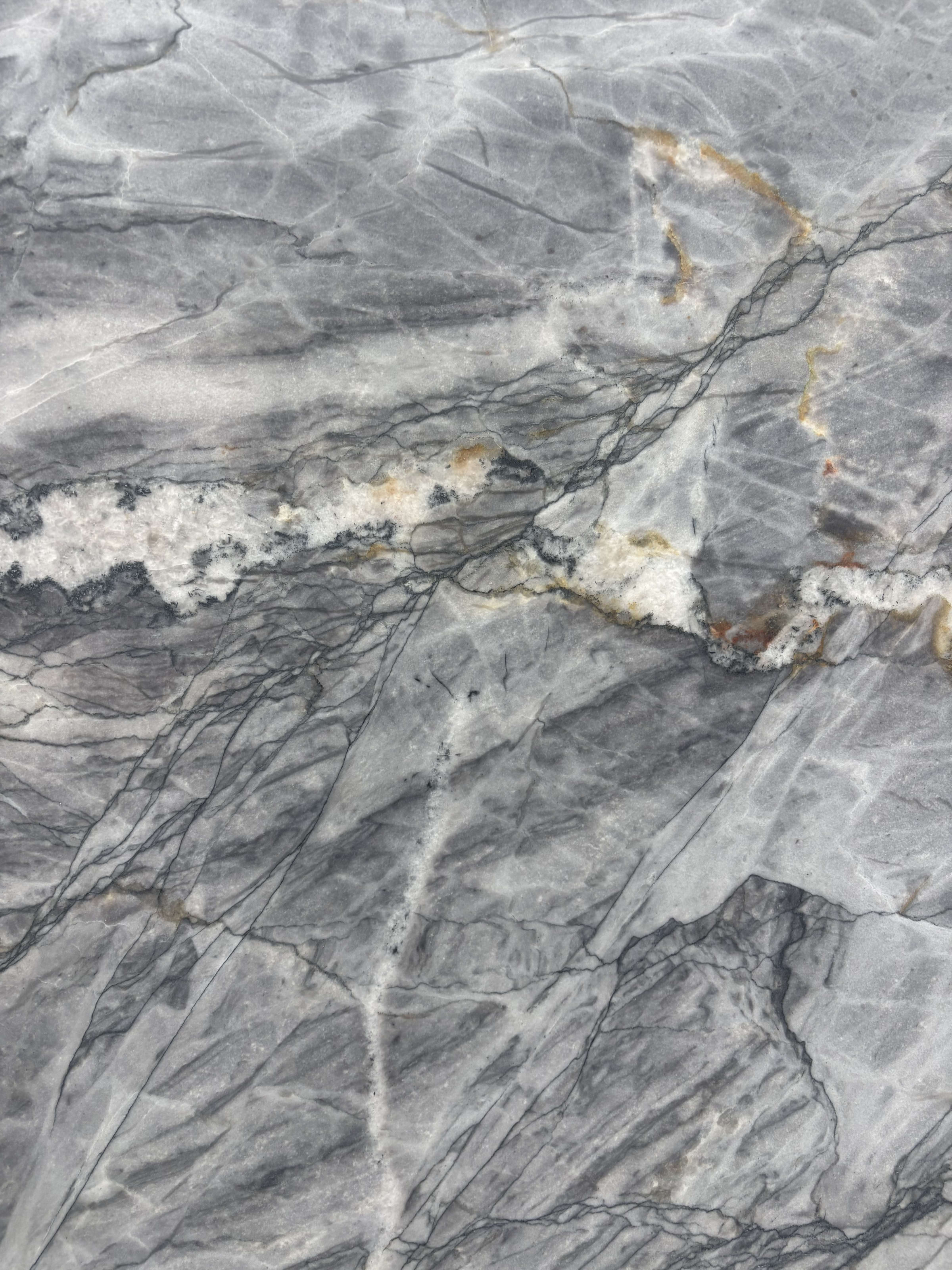 Manhattan quartzite detail, pale quartz and olive-gold seams breaking across a deep blue-grey ground