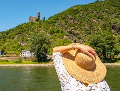 Woman with sun hat looking at a castle from her river ship during daytime