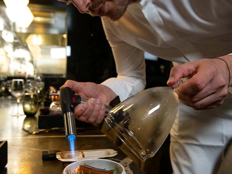 Chef using a blowtorch to prepare a plated dish