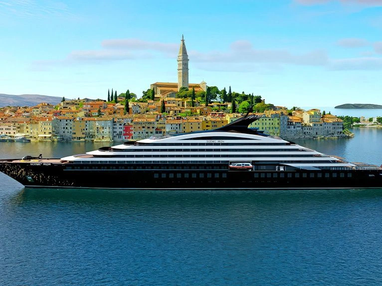 Scenic Ikon Discovery Yacht CGI alongside a historic coastal town