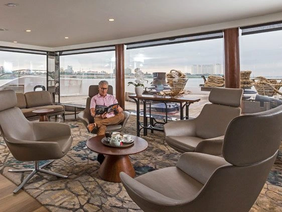 Onboard library with leather chairs and large windows overlooking a river