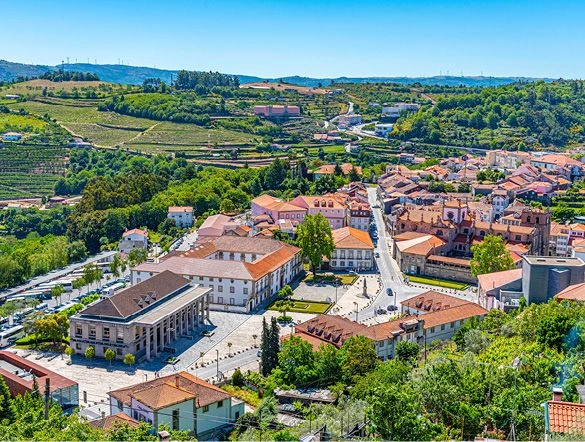 An aerial view of Lamego city centre in Portugal. Vineyards and green hills are seen in the background.