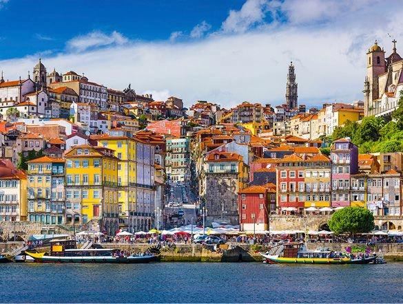 A view of Porto in Portugal. The old town skyline and colourful buildings can be seen from across the Douro River.