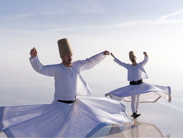 Two men dressed in traditional white costumes performing a Whirling dervish dance