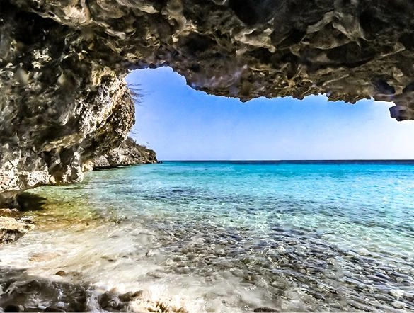 A scenic cave looking out to the calm clear blue waters of the Caribbean Sea