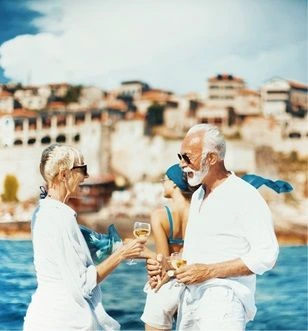 A couple dressed in white enjoying a glass of white wine overlooking the sea and coast of the Mediterranean