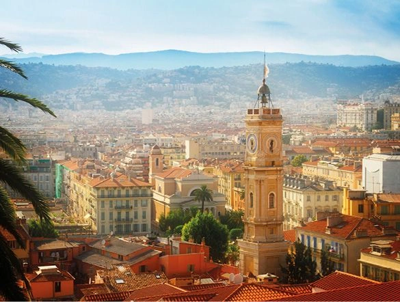 Cityscape of Nice with beautiful golden architecture and a backdrop of hillside and bright blue skies 
