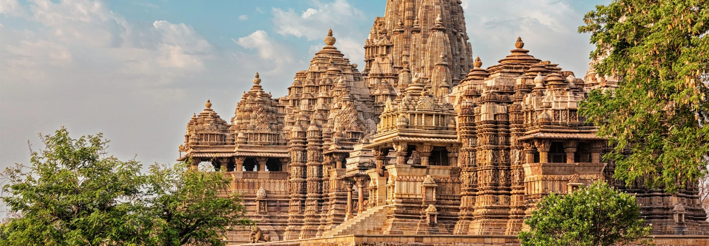 Ornately carved stone temples rise above gardens in Khajuraho
