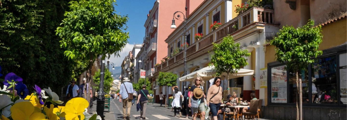 Pedestrians walk past cafés and shops on a Sorrento street