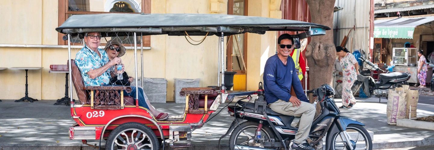 Guests ride in a tuk tuk through Phnom Penh
