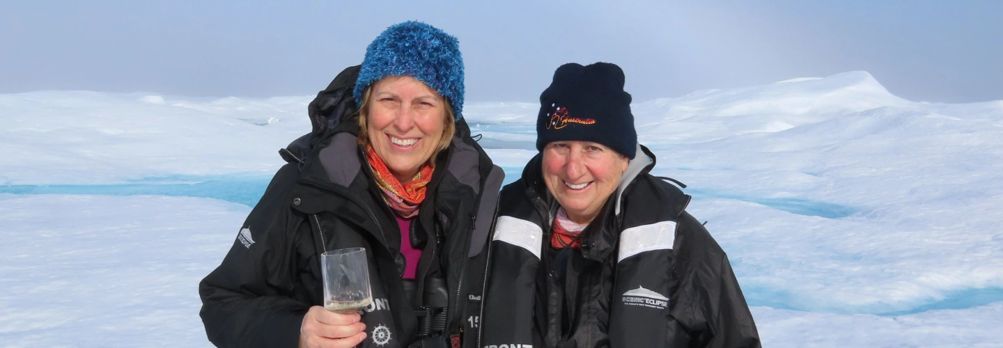 Two guests in expedition gear stand on Arctic sea ice