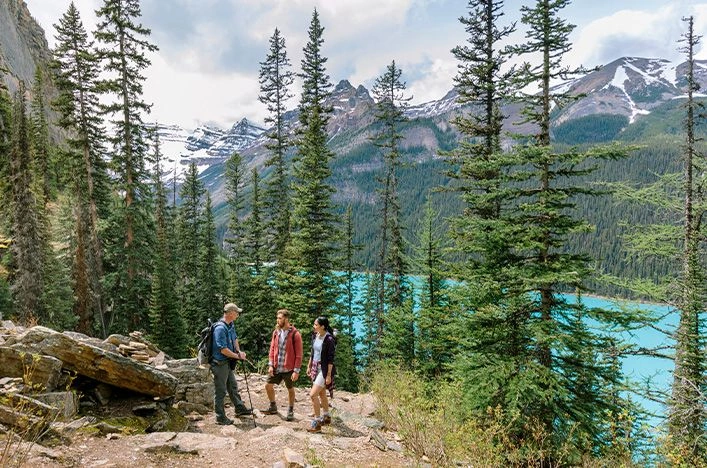 Three hikers on a forest trail above Lake Louise