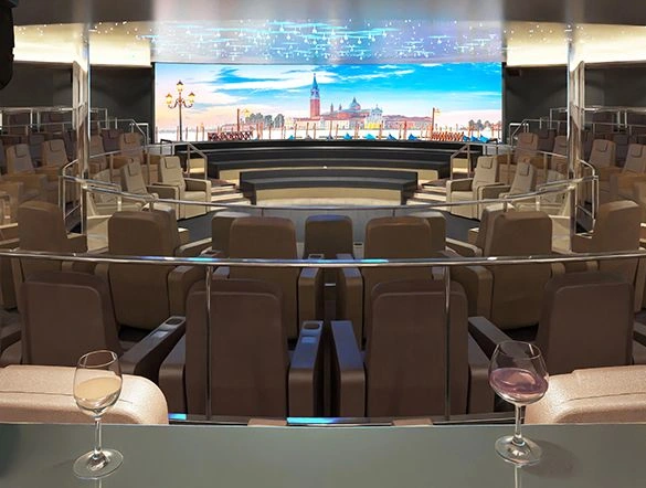 Tiered theatre-style lounge with reclining seats and drinks facing a large scenic screen