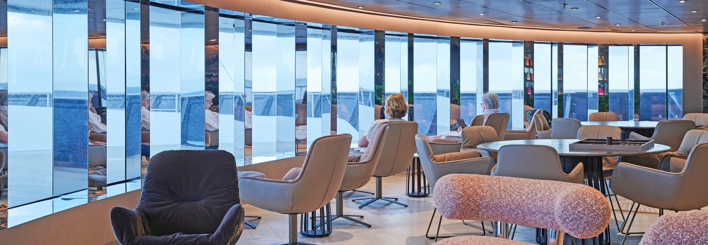 Guests relaxing in a light-filled Scenic observation lounge with panoramic ocean views
