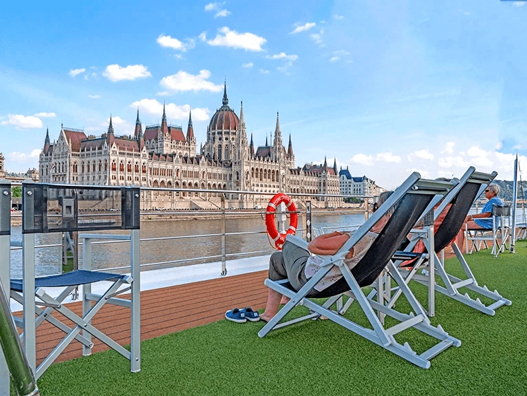 Guests on the sun deck of a Scenic cruise ship in Budapest, looking at the Hungarian Parliament Building.