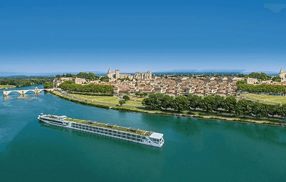 The Scenic Sapphire ship cruising past the historic city of Avignon on the Rhone River, under a clear blue sky.